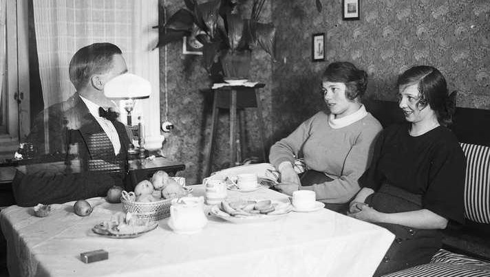 En genomskinlig man sitter vid ett bord tillsammans med två kvinnor.