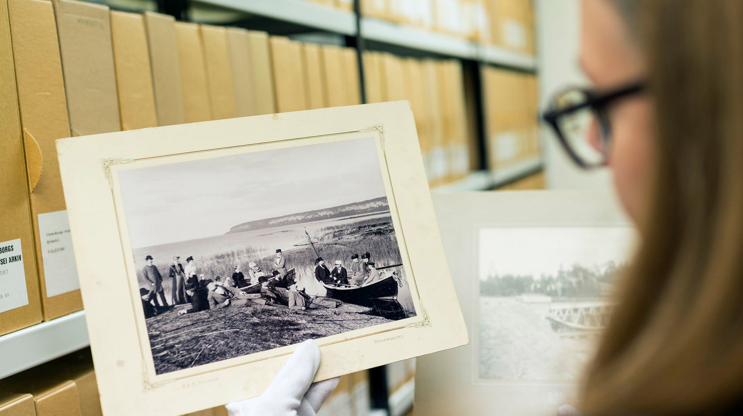 En kvinna står och tittar på ett fotografi som hon håller i.