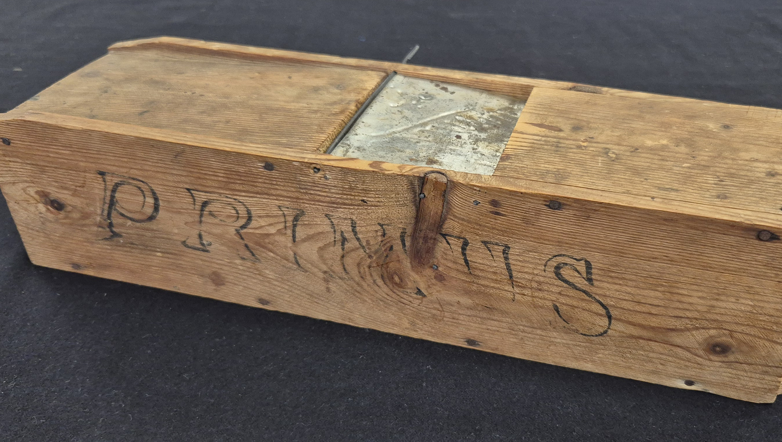 En avlång trälåda som är en äldre råttfälla. På lådan står "Primus".