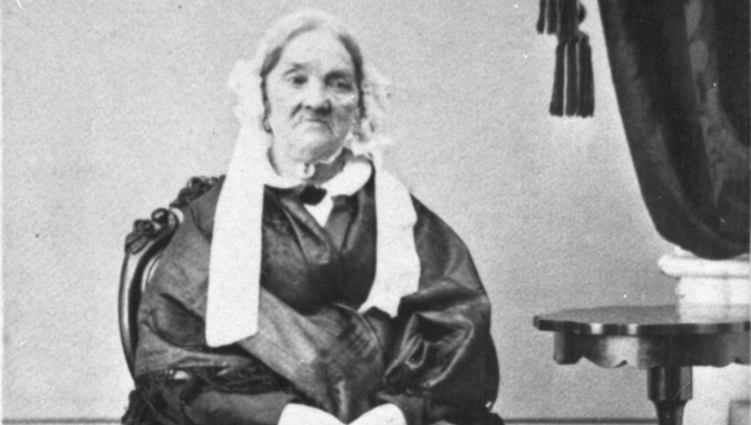 En äldre kvinna sitter på en stol.