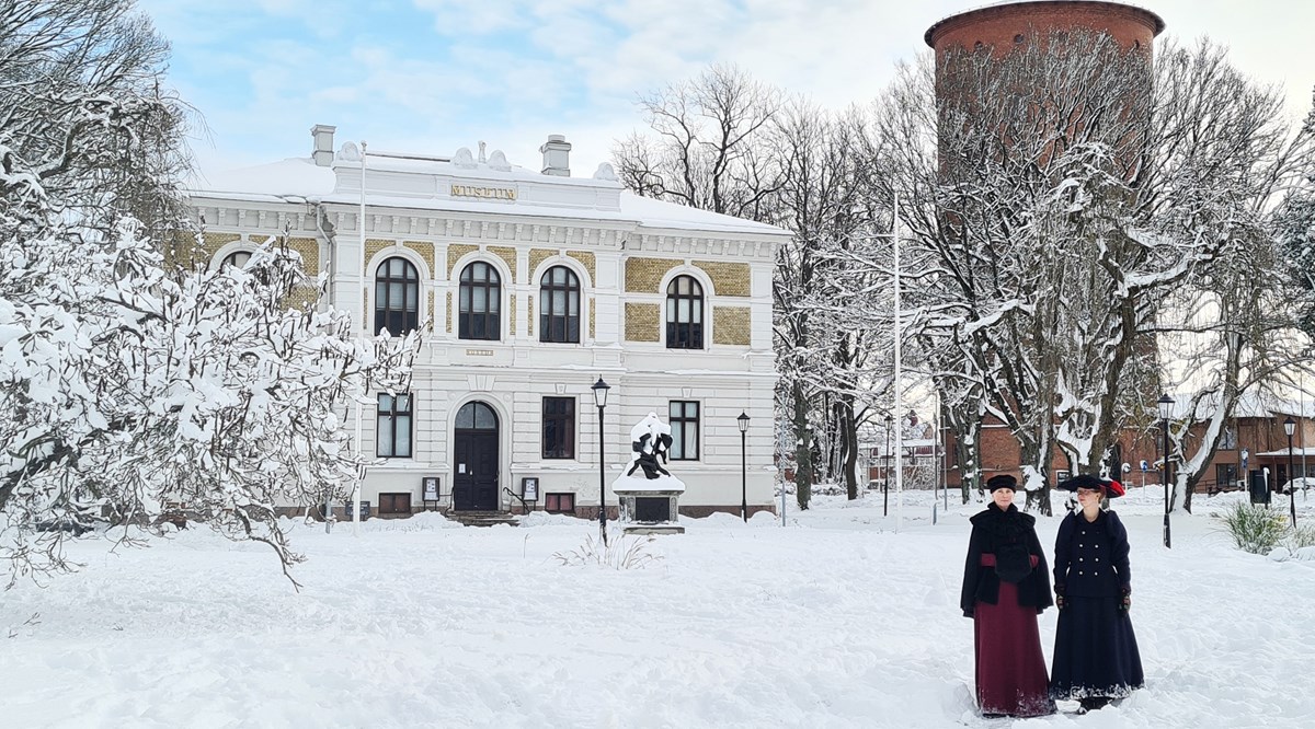 Två kvinnor i 1800-talskläder står framför Vänersborgs museum.