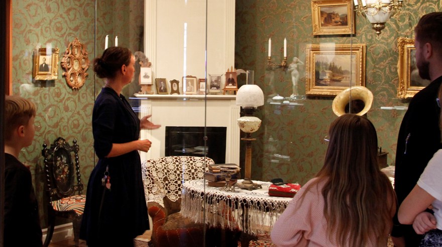 Kvinna visar rum bakom glas för grupp.