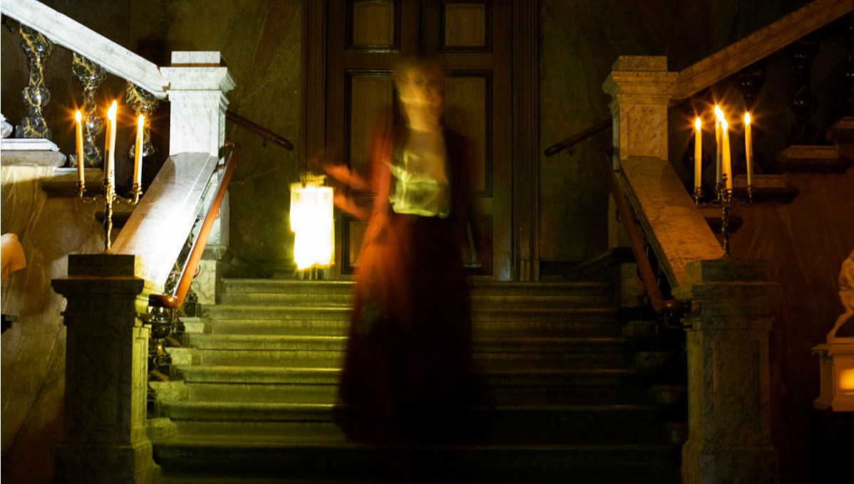 En suddig figur går ner för trappan i trapphallen på Vänersborgs museum.