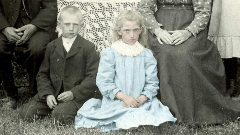 Edit Augustsson sittande i gräset bredvid sin bror.