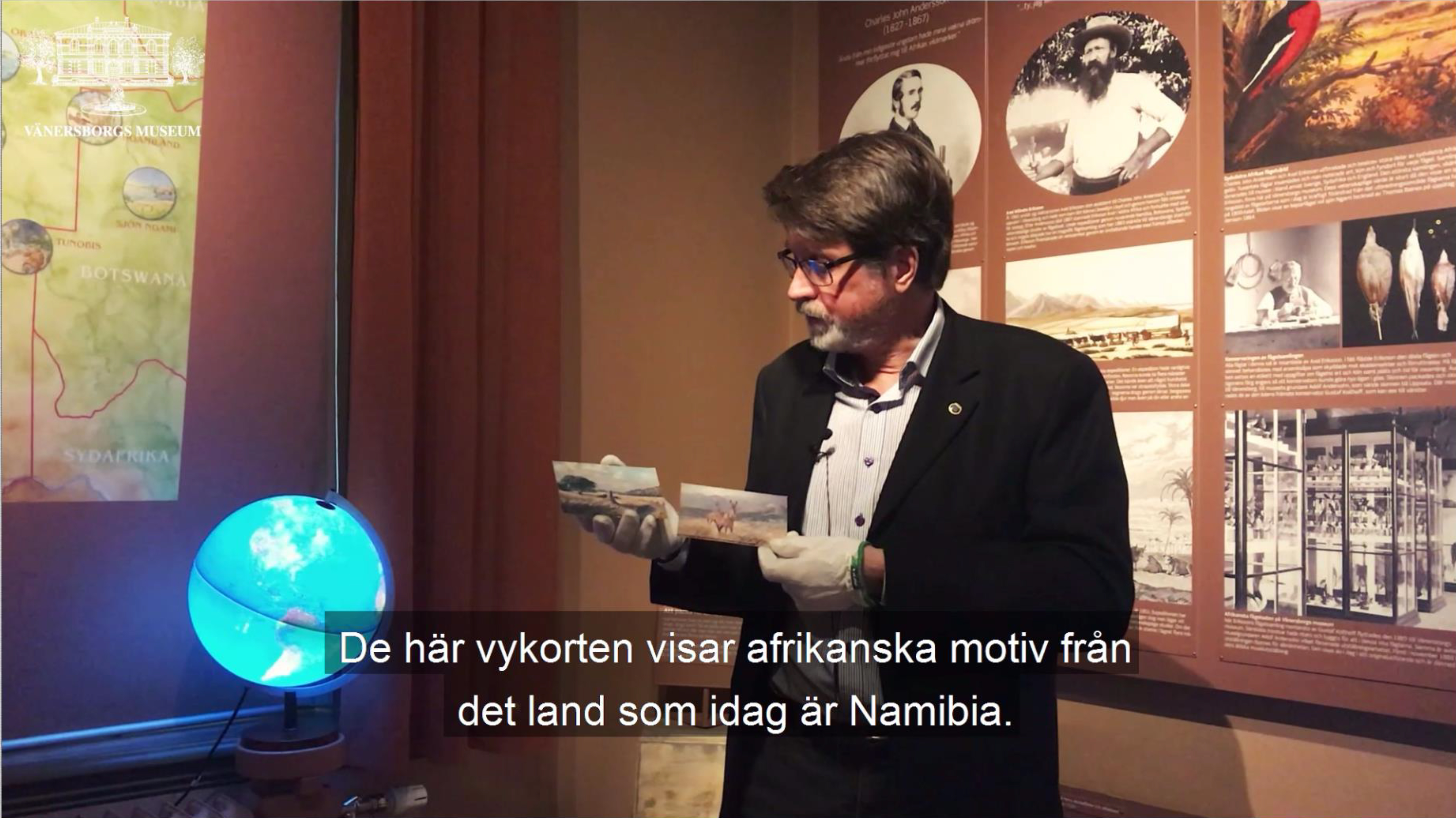 Peter Johansson visar två vykort med motiv av Axel Eriksson Jr.