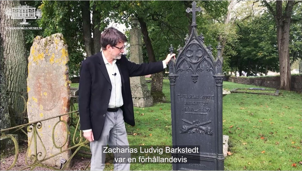 Peter Johansson står framför en gravvård av järn tillhörande Zacharias Ludvig Barkstedt.