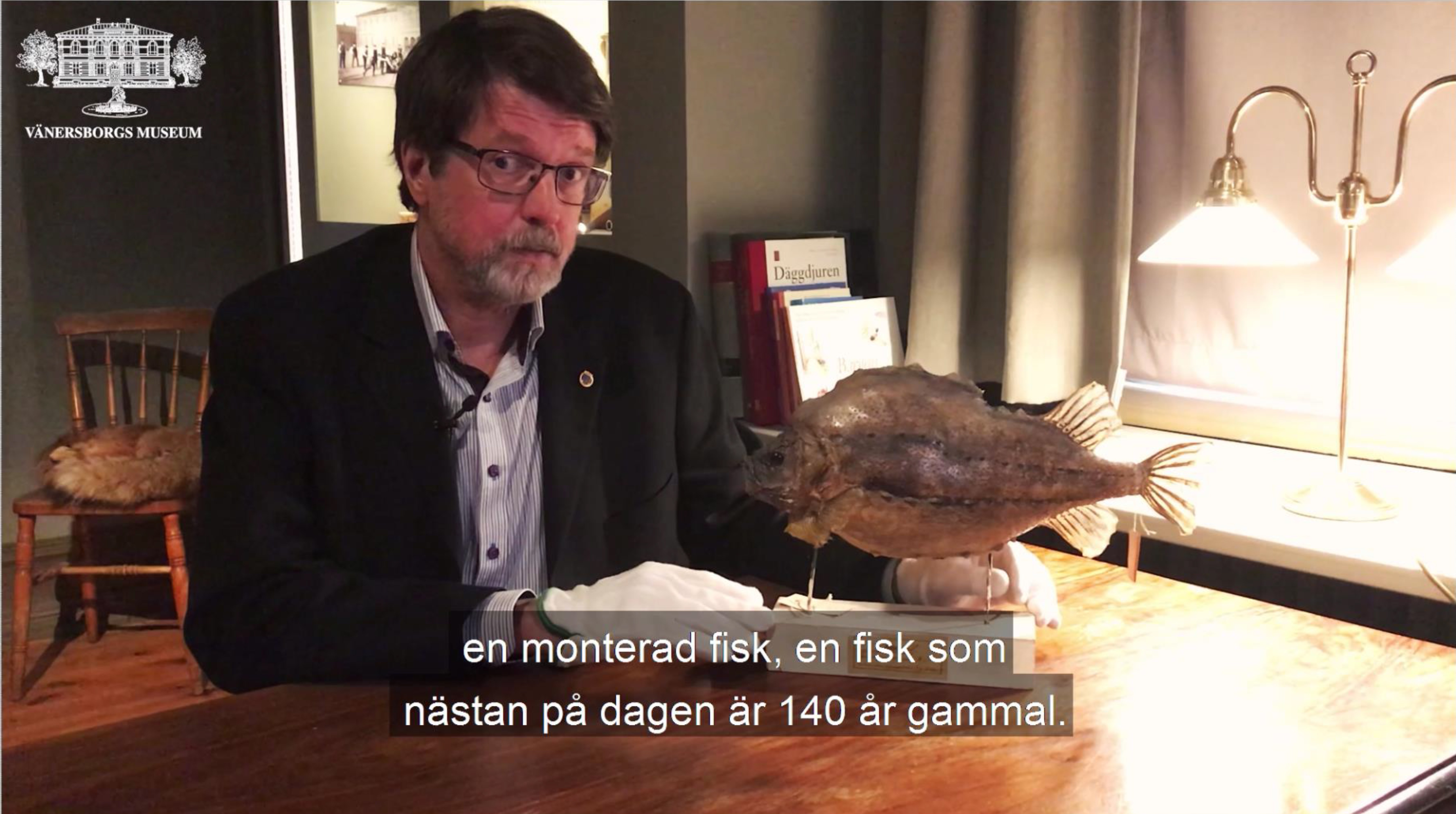 Museichef Peter Johansson sitter vid ett bord med en monterad fisk.