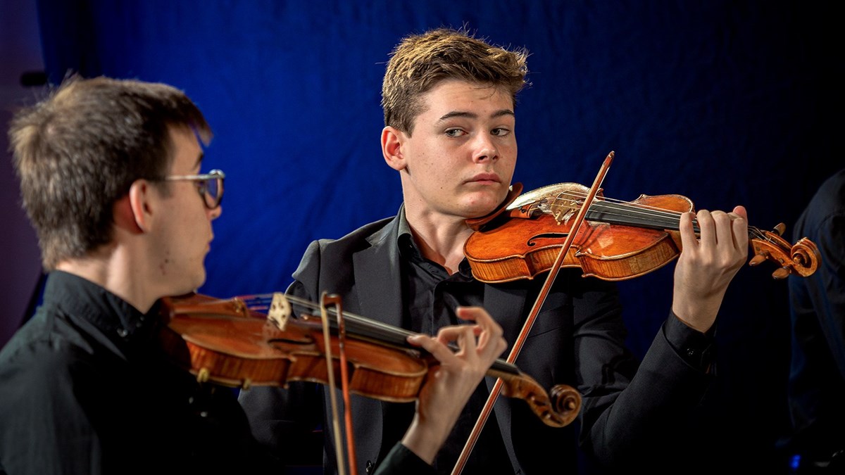Två unga män som spelar fiol.