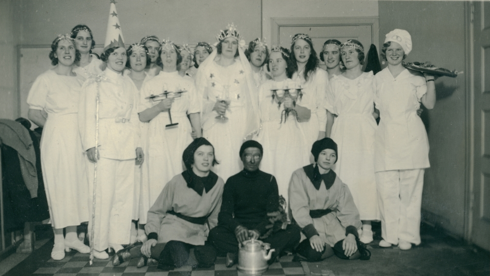 Luciatåg med kvinnor utklädda till tärnor, stjärngosse, bagare, tomtar och Svarte Petter.