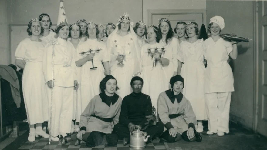 Luciatåg med kvinnor utklädda till tärnor, stjärngosse, bagare, tomtar och Svarte Petter.