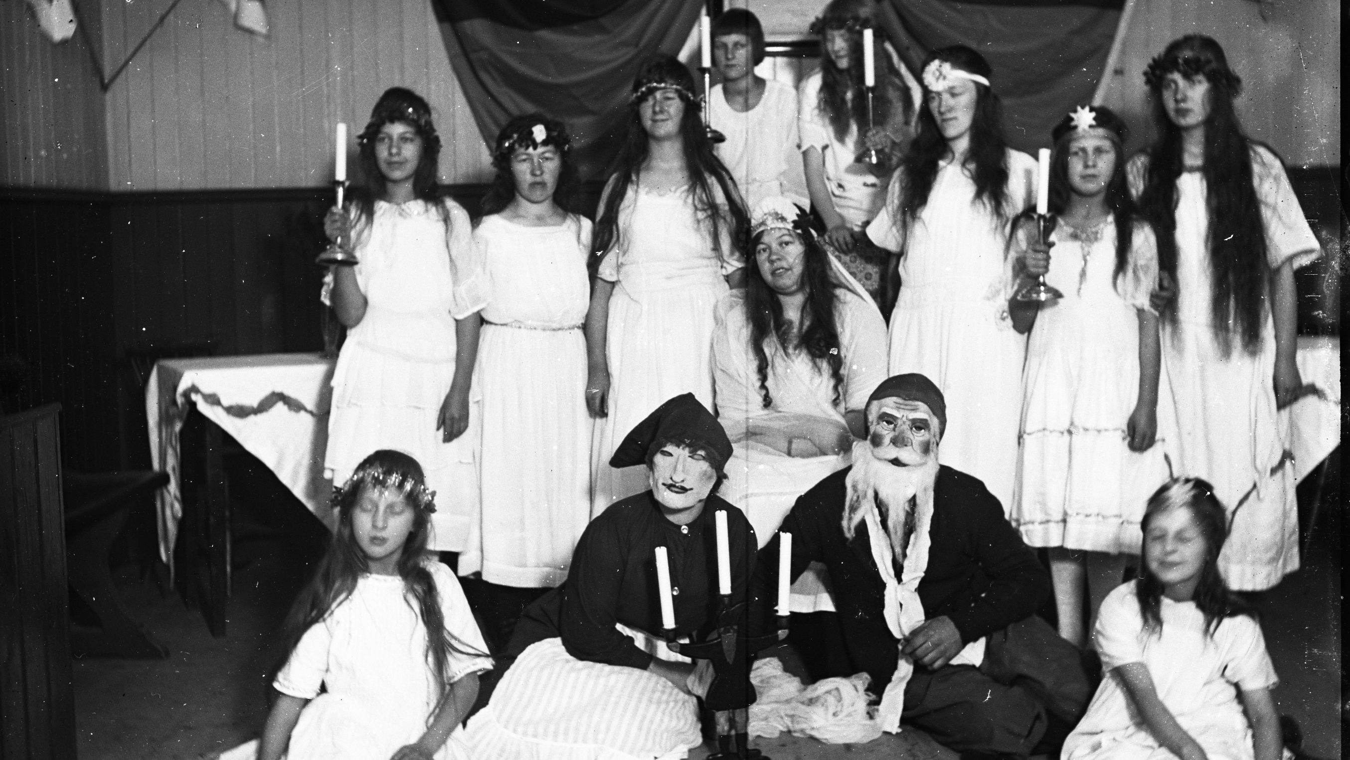 Personer utklädda till tärnor och tomtar inför ett julspel eller luciatåg.