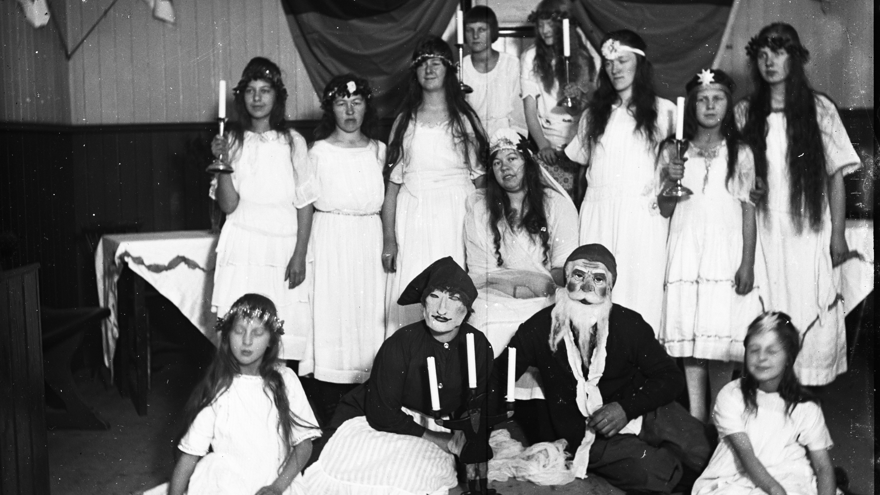 Personer utklädda till tärnor och tomtar inför ett julspel eller luciatåg.